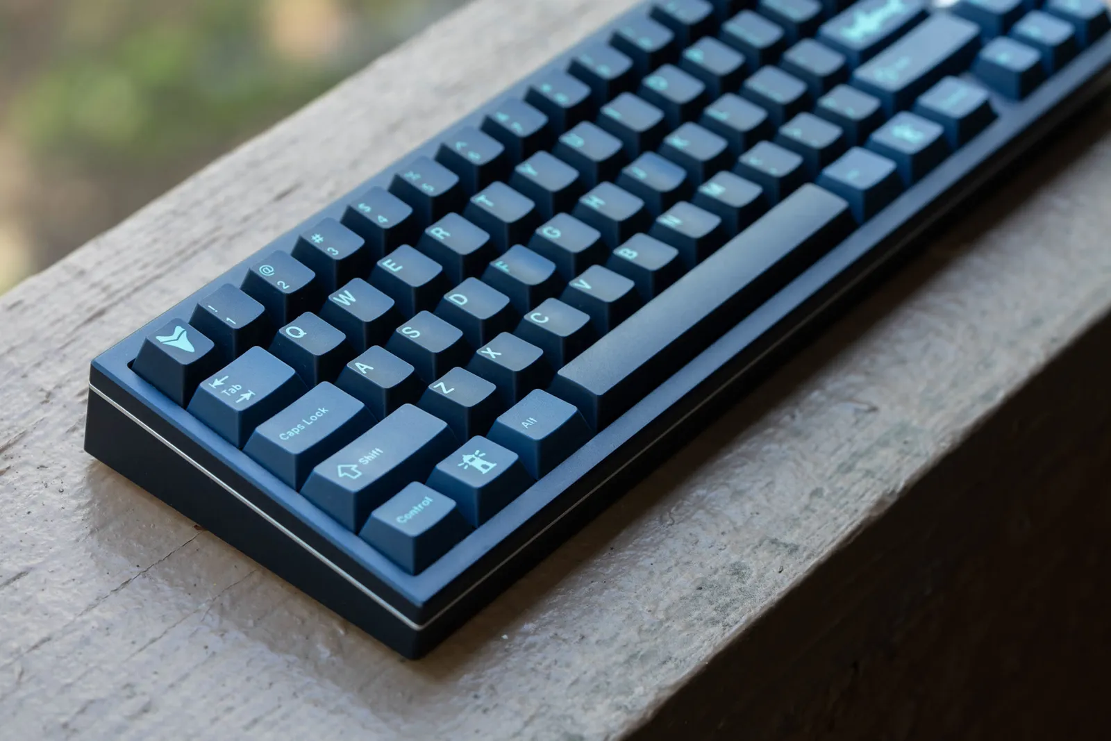 The Aozora 69: a dark-blue milled-aluminum 65% mechanical keyboard on a wooden ledge.